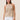 Woman wearing a beige crochet halter top against a beige background