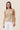 Woman wearing a beige crochet halter top against a beige background