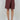 Women’s burgundy high-waisted Bermuda shorts with asymmetric wrap front, side buckle and tie detail.
