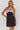 Woman wearing a black dress with a silver bow detail on a white background