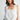 Women's white sleeveless embroidered blouse featuring eyelet lace trim, floral embroidery, scalloped details, and an adjustable tie neckline.