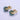 Pair of gold and green earrings on a light purple background