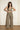 Women’s taupe two-piece set with halter crop top, wide-leg pants and fringe wrap waist detail.