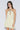 Woman wearing a light yellow halter neck dress against a plain background