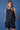 Woman wearing a navy blue sleeveless top and shorts with white polka dots against a blue background