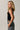 Women's black ribbed sleeveless sweater tank with side button detail and asymmetrical hem.