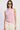 Woman wearing a pink sleeveless top and white pants on a light gray background